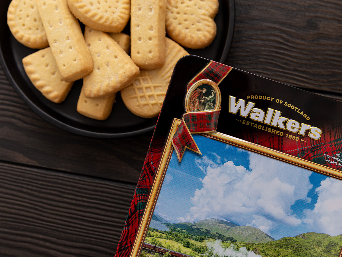 Shortbread on a wooden table top along with the corner of a Walker's Shortbread tin.